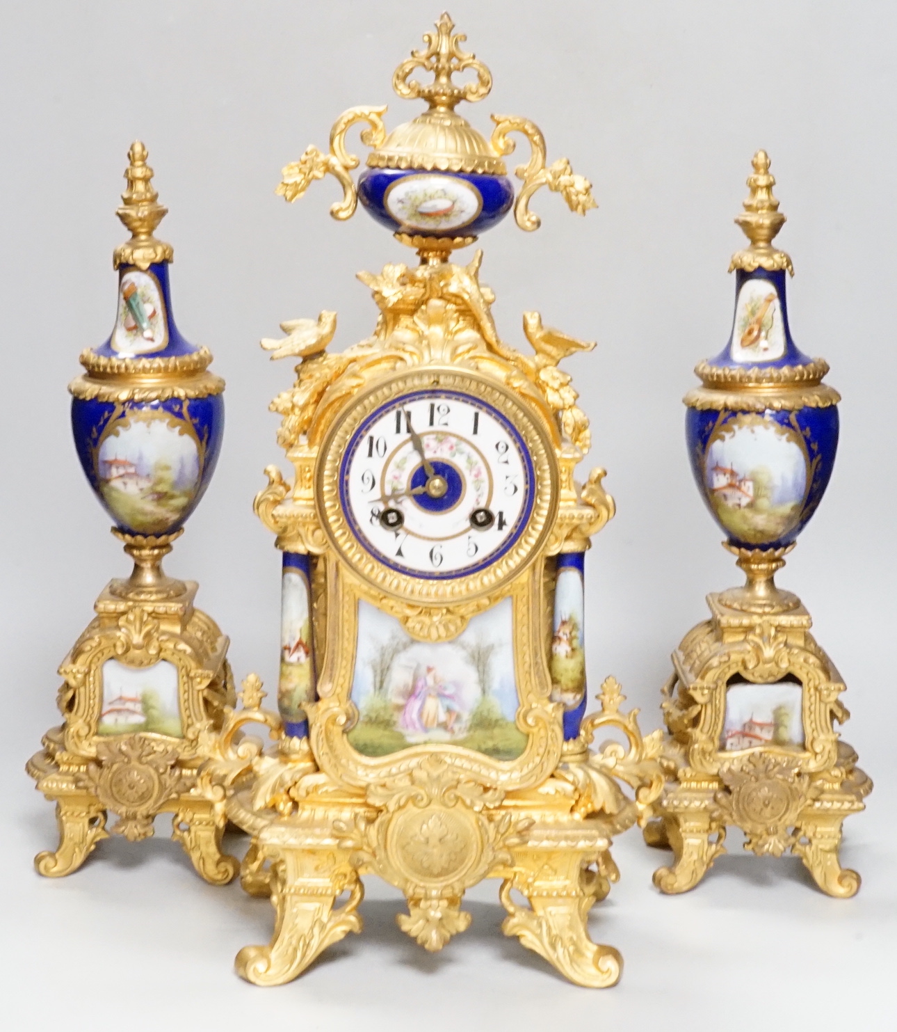 An early 20th century French gilt metal and porcelain set clock garniture, 42cm